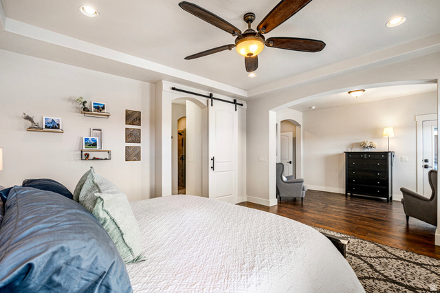 2311 South 1340 West St. George, UT 84770 - Photo 31 of 56 Bedroom with a barn door, recessed lighting, dark wood-style flooring, a ceiling fan, and arched walkways