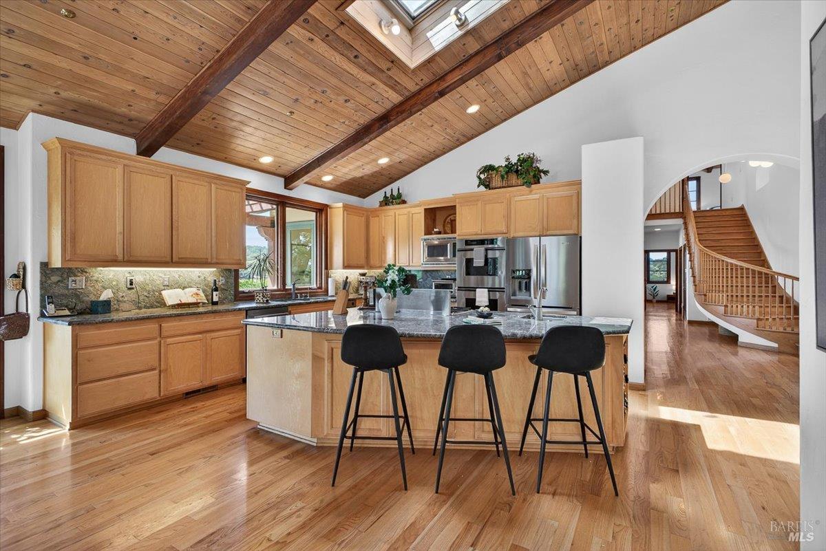 13404 Flora Ranch Road Healdsburg, CA 95448 - Photo 32 of 83 a kitchen with stainless steel appliances kitchen island granite countertop a table chairs and a wooden floor