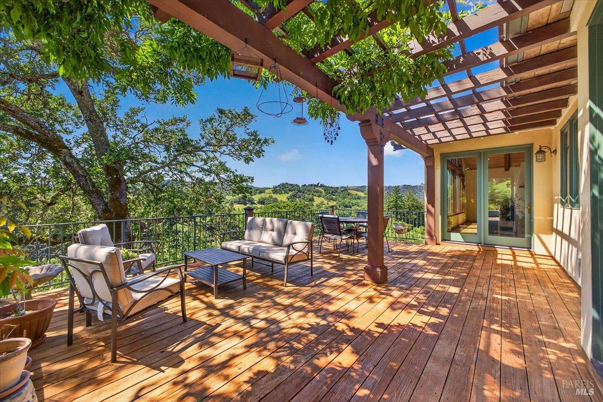 13404 Flora Ranch Road Healdsburg, CA 95448 - Photo 62 of 83 a view of a patio with a dining table and chairs with wooden floor and fence