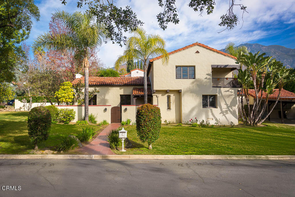 a front view of a house with a garden and trees