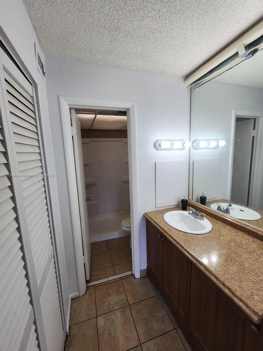 3690 Inverrary Drive, Unit 1T Lauderhill, FL 33319 - Photo 22 of 24 a spacious bathroom with a sink a mirror and a shower