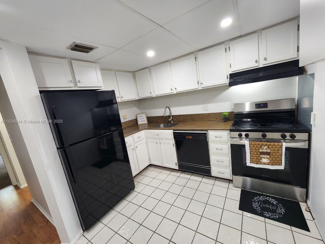 3690 Inverrary Drive, Unit 1T Lauderhill, FL 33319 - Photo 10 of 24 a kitchen with a sink a stove and cabinets