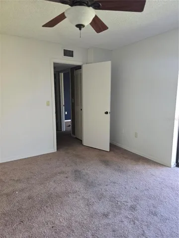 an empty room with closet and a ceiling fan
