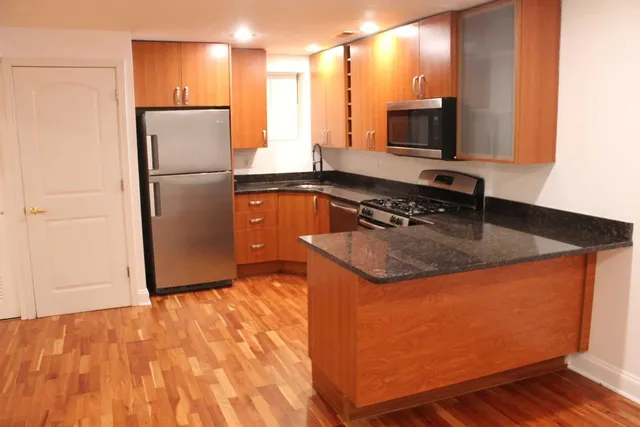 a kitchen with stainless steel appliances granite countertop a refrigerator a sink and a stove