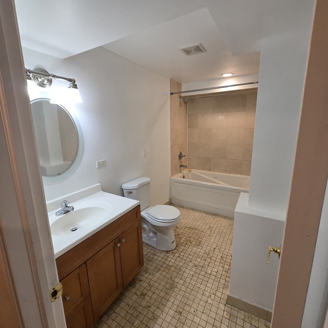 4944 North Spaulding Avenue, Unit G Chicago, IL 60625 - Photo 7 of 9 a bathroom with a granite countertop toilet a sink and a mirror
