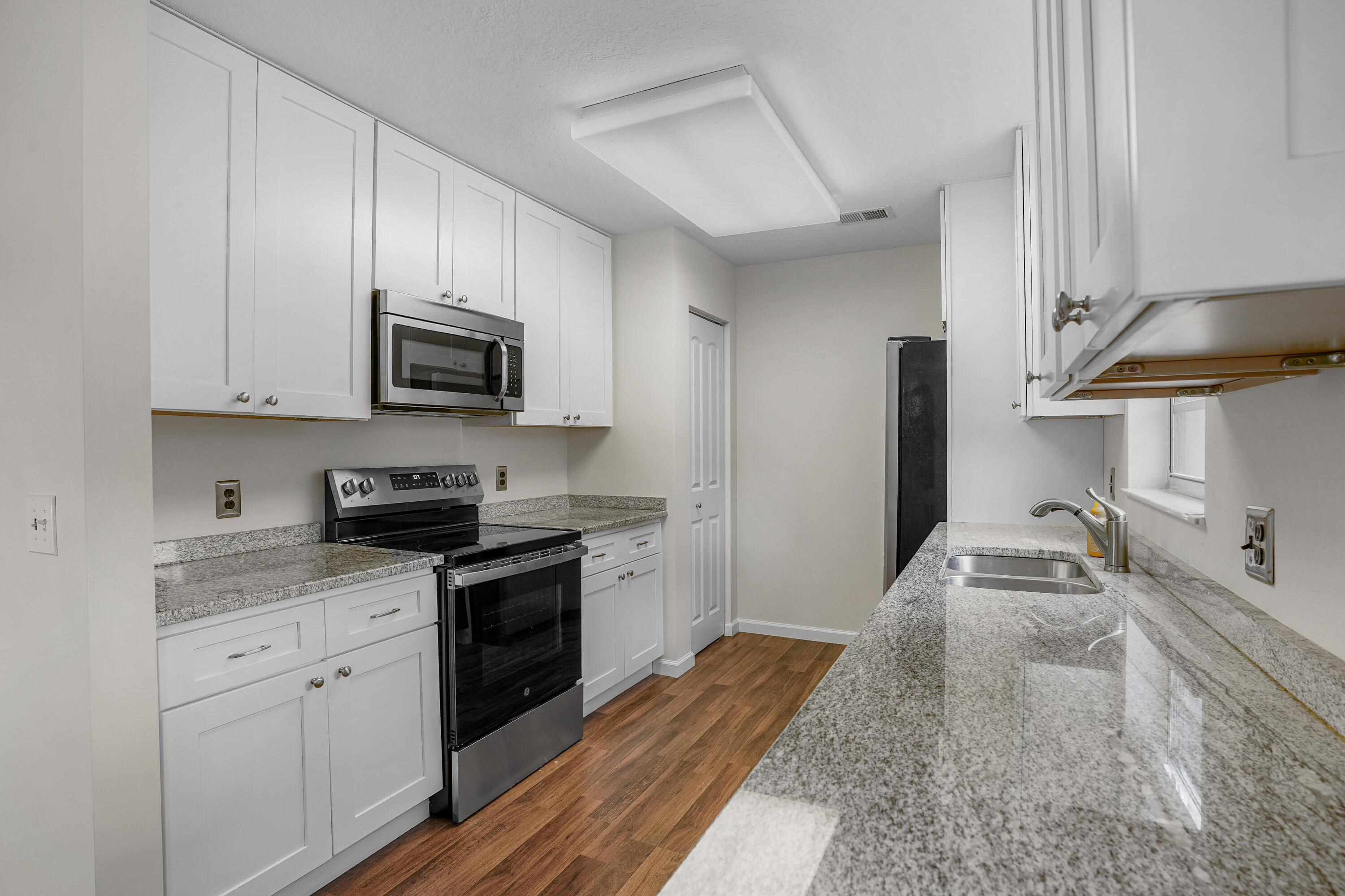 23 Lake Vista Trail, Unit 101 Port St. Lucie, FL 34952 - Photo 11 of 24 a kitchen with granite countertop a sink stove and refrigerator