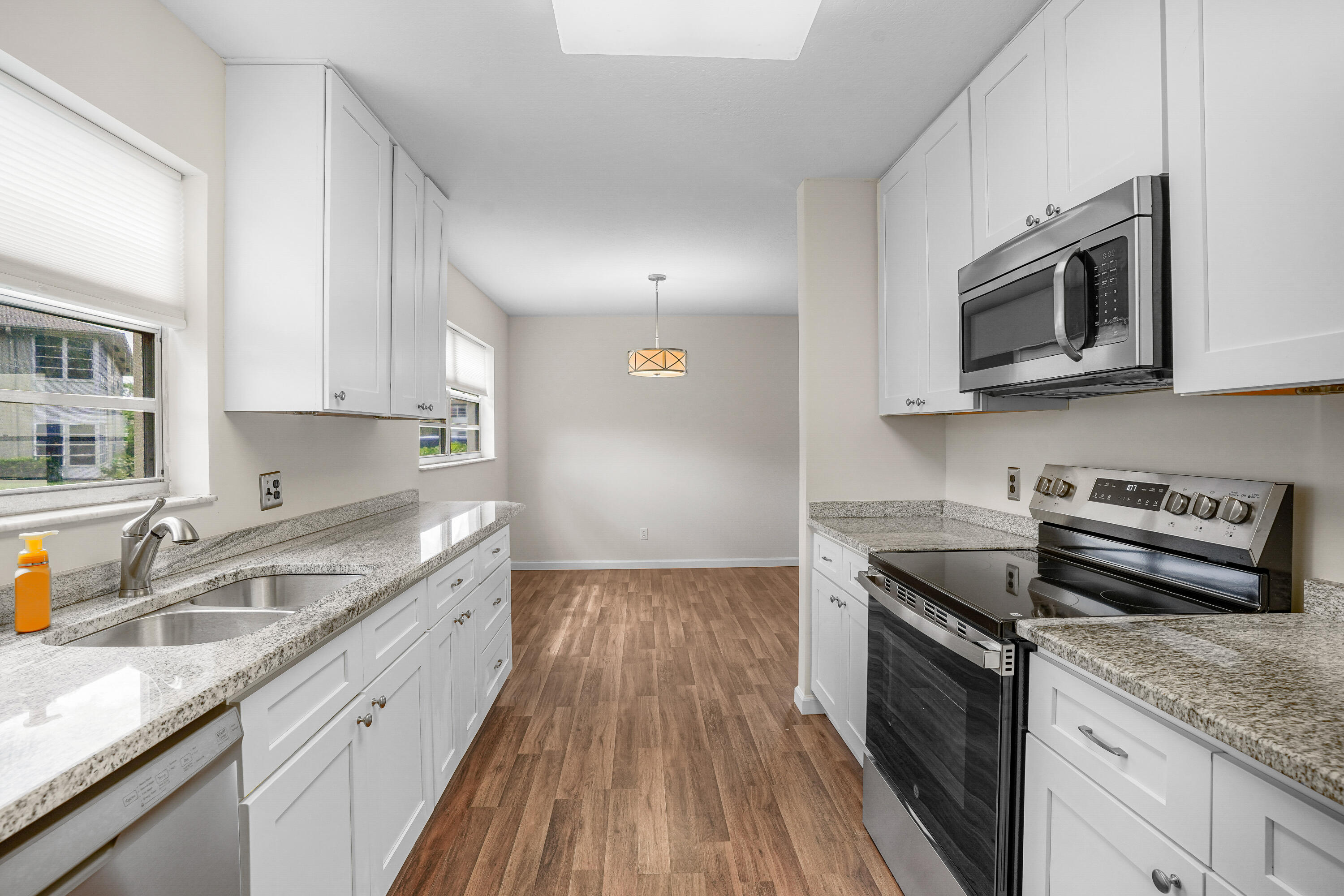 23 Lake Vista Trail, Unit 101 Port St. Lucie, FL 34952 - Photo 12 of 24 a kitchen with granite countertop a sink dishwasher stove and microwave with wooden floor
