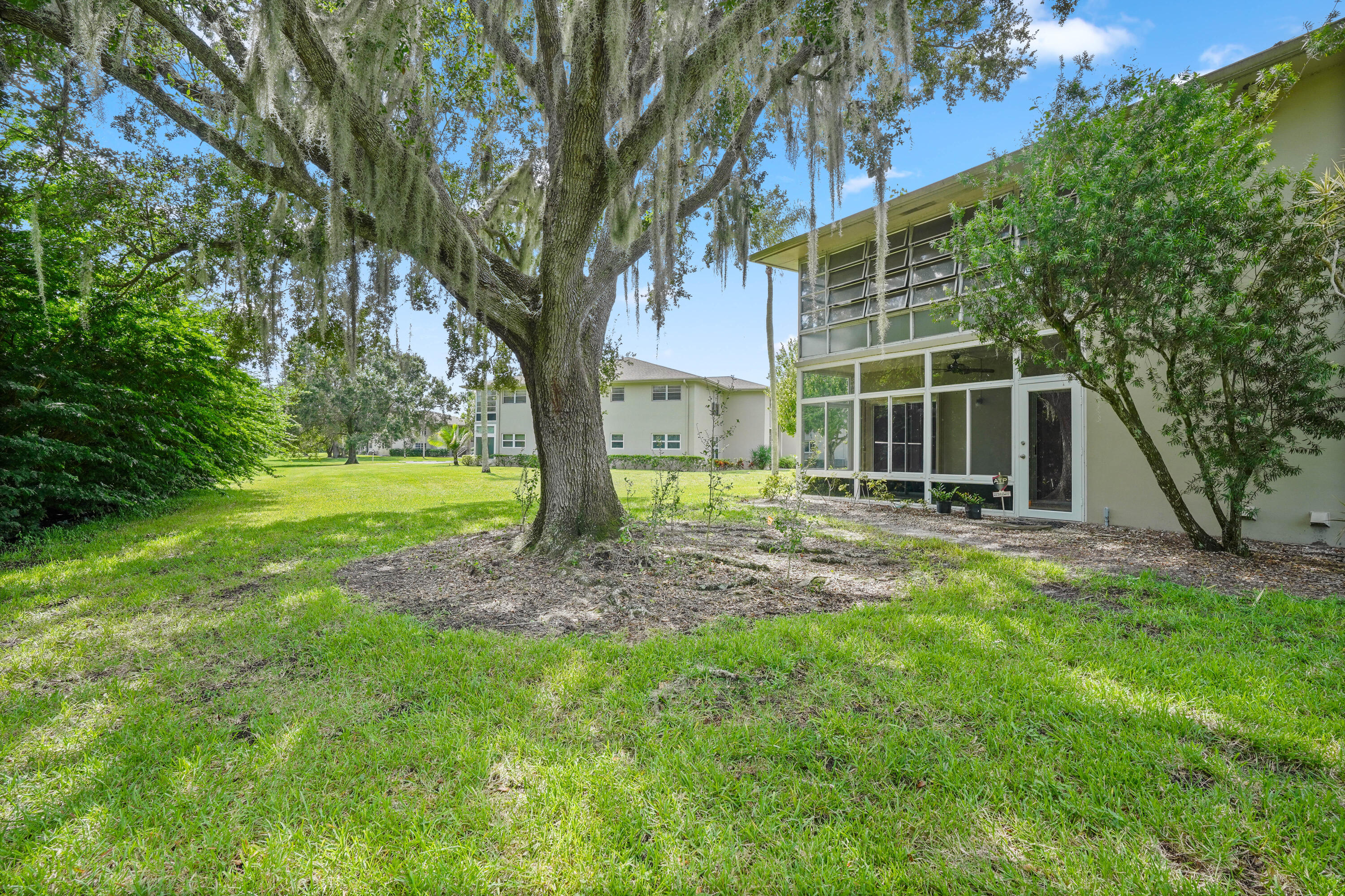 23 Lake Vista Trail, Unit 101 Port St. Lucie, FL 34952 - Photo 21 of 24 a view of a yard with plants and large trees