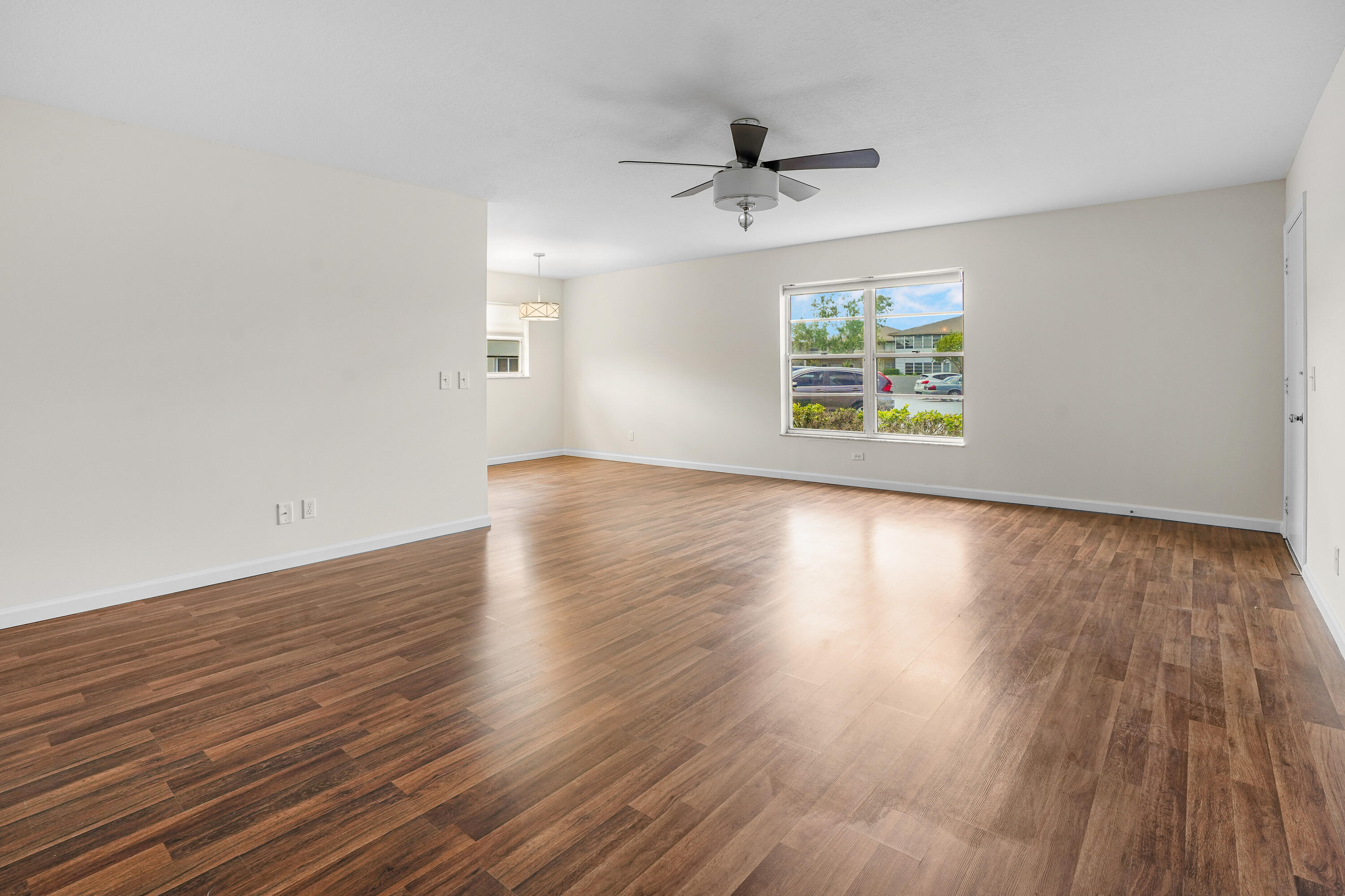 23 Lake Vista Trail, Unit 101 Port St. Lucie, FL 34952 - Photo 7 of 24 a view of an empty room with wooden floor and a window