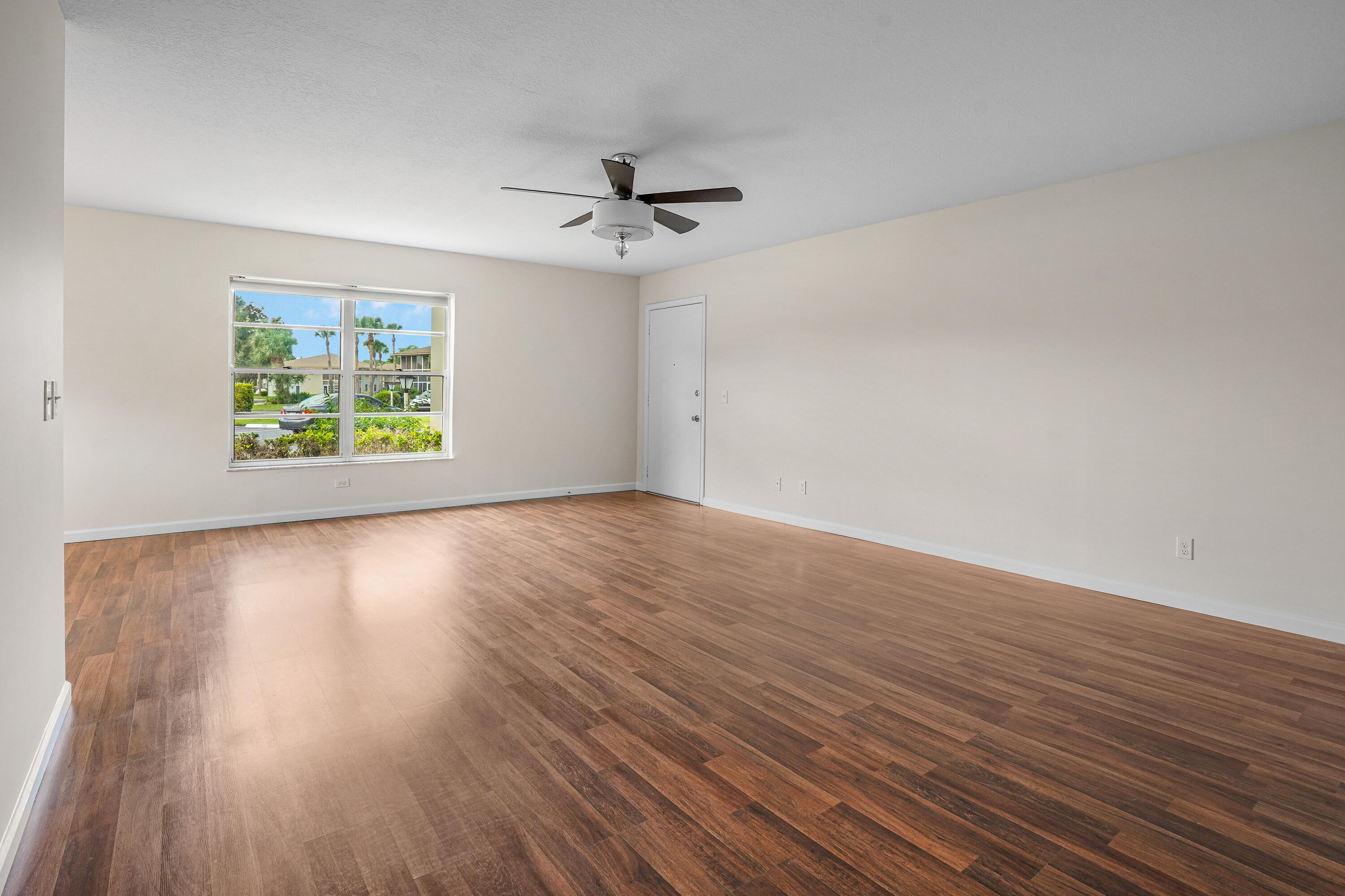 23 Lake Vista Trail, Unit 101 Port St. Lucie, FL 34952 - Photo 8 of 24 an empty room with wooden floor window and ceiling fan