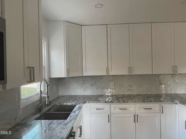 a kitchen with granite countertop a sink a stove and cabinets