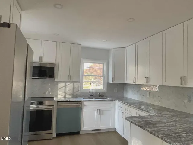 a kitchen with stainless steel appliances granite countertop a stove a sink and a refrigerator