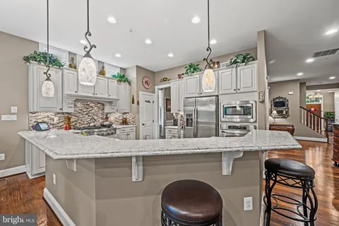 a kitchen with stainless steel appliances granite countertop a sink a stove and a wooden floors