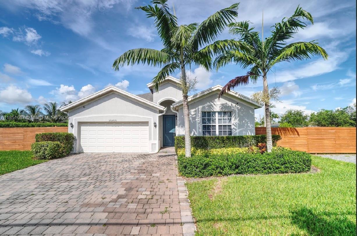 30600 Southwest 193rd Avenue Homestead, FL 33030 - Photo 1 of 36 a front view of a house with a yard and garage