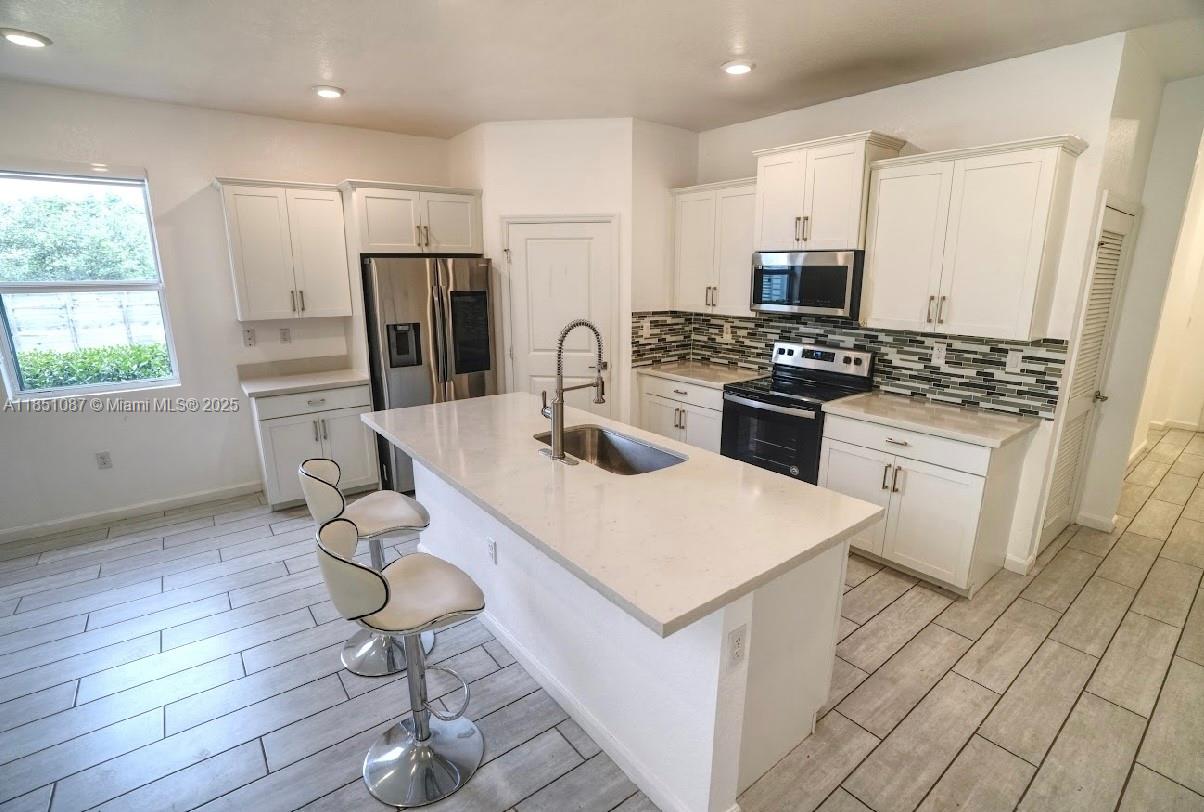 30600 Southwest 193rd Avenue Homestead, FL 33030 - Photo 31 of 36 a kitchen with stainless steel appliances a stove a refrigerator a sink a dining table and chairs