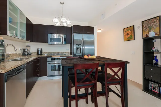 a kitchen with stainless steel appliances granite countertop a dining table and chairs