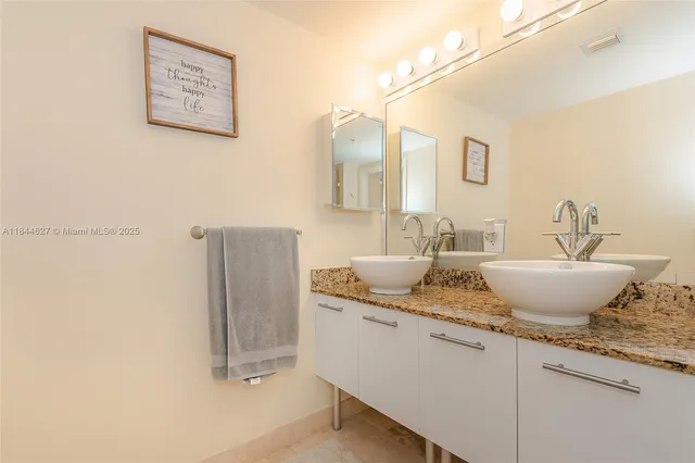 a bathroom with a granite countertop sink a toilet a mirror and shower