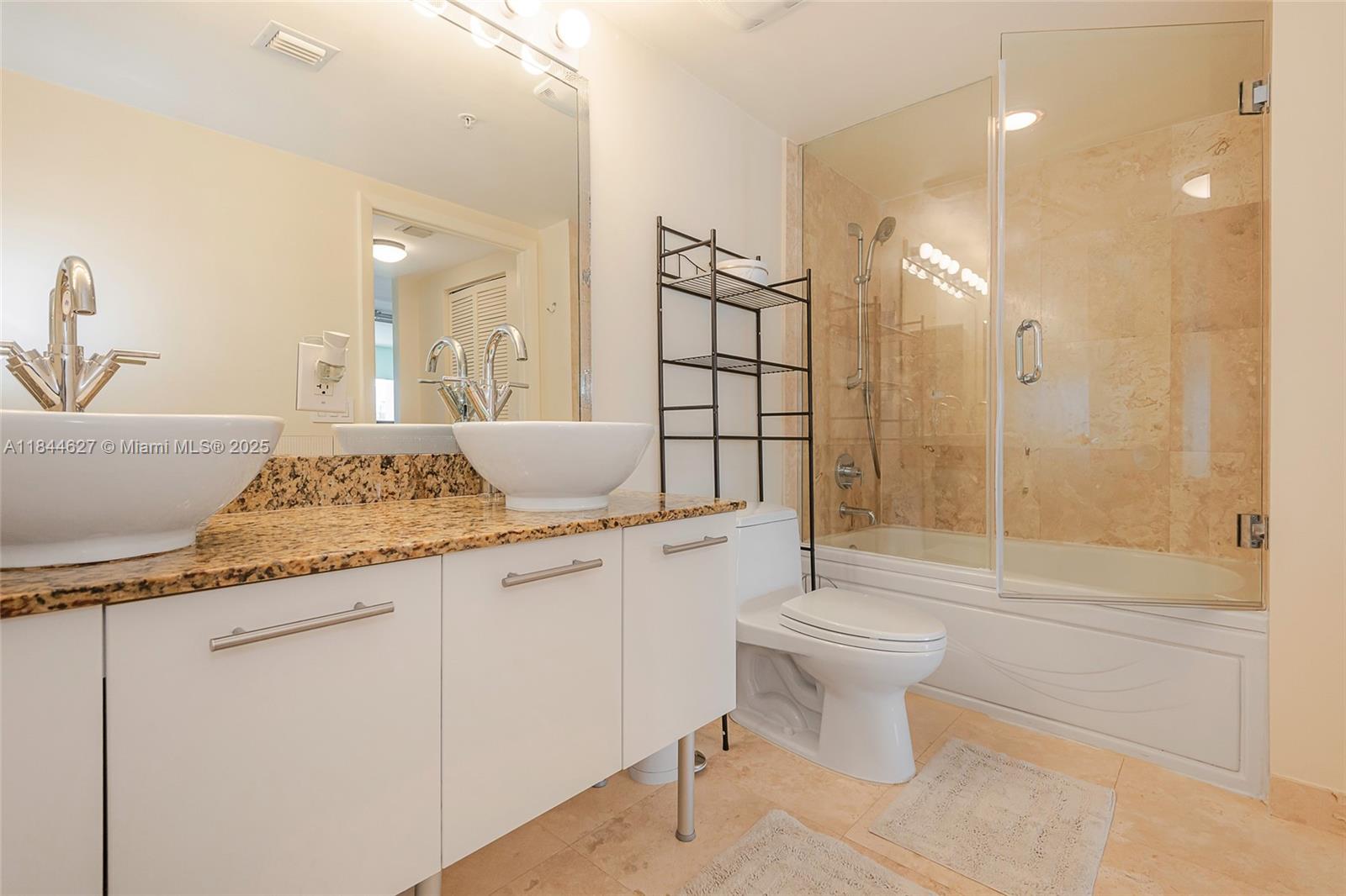 41 Southeast 5th Street, Unit 1503 Miami, FL 33131 - Photo 26 of 27 a bathroom with a granite countertop sink a toilet a mirror and shower