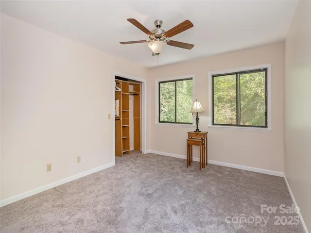 an empty room with windows and ceiling fan