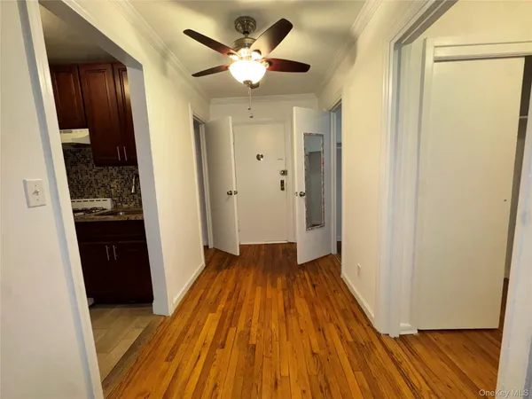 a view of a hallway with wooden floor and a kitchen space