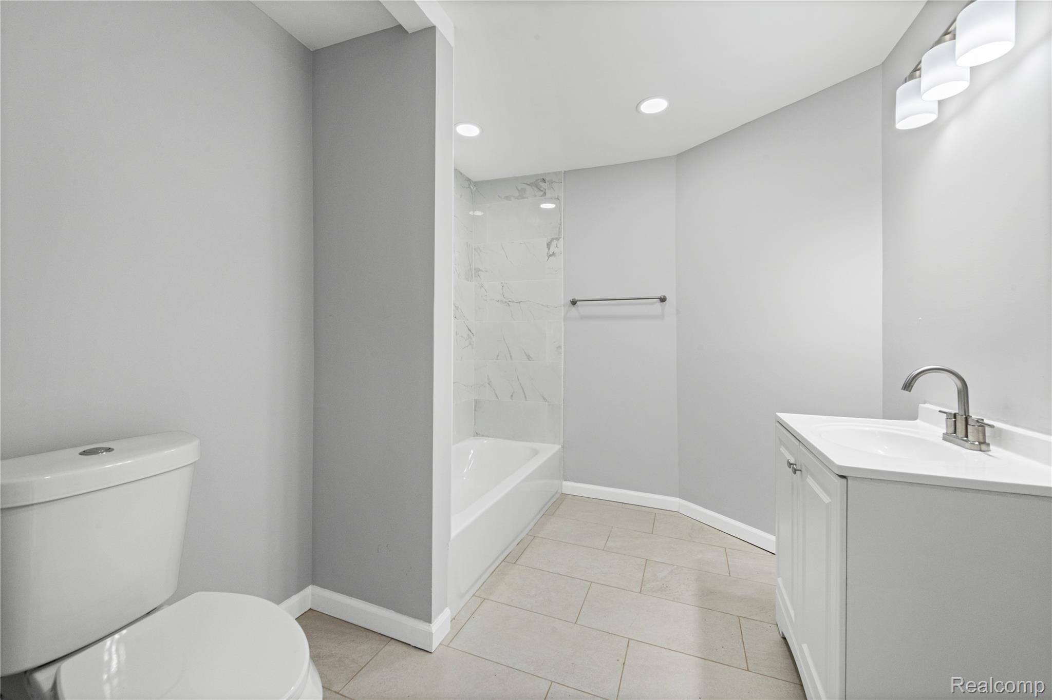 9175 Devonshire Road Detroit, MI 48224 - Photo 11 of 26 Bathroom featuring a white vanity with integrated sink, brushed nickel faucet, and a shower-tub combination with tile surround