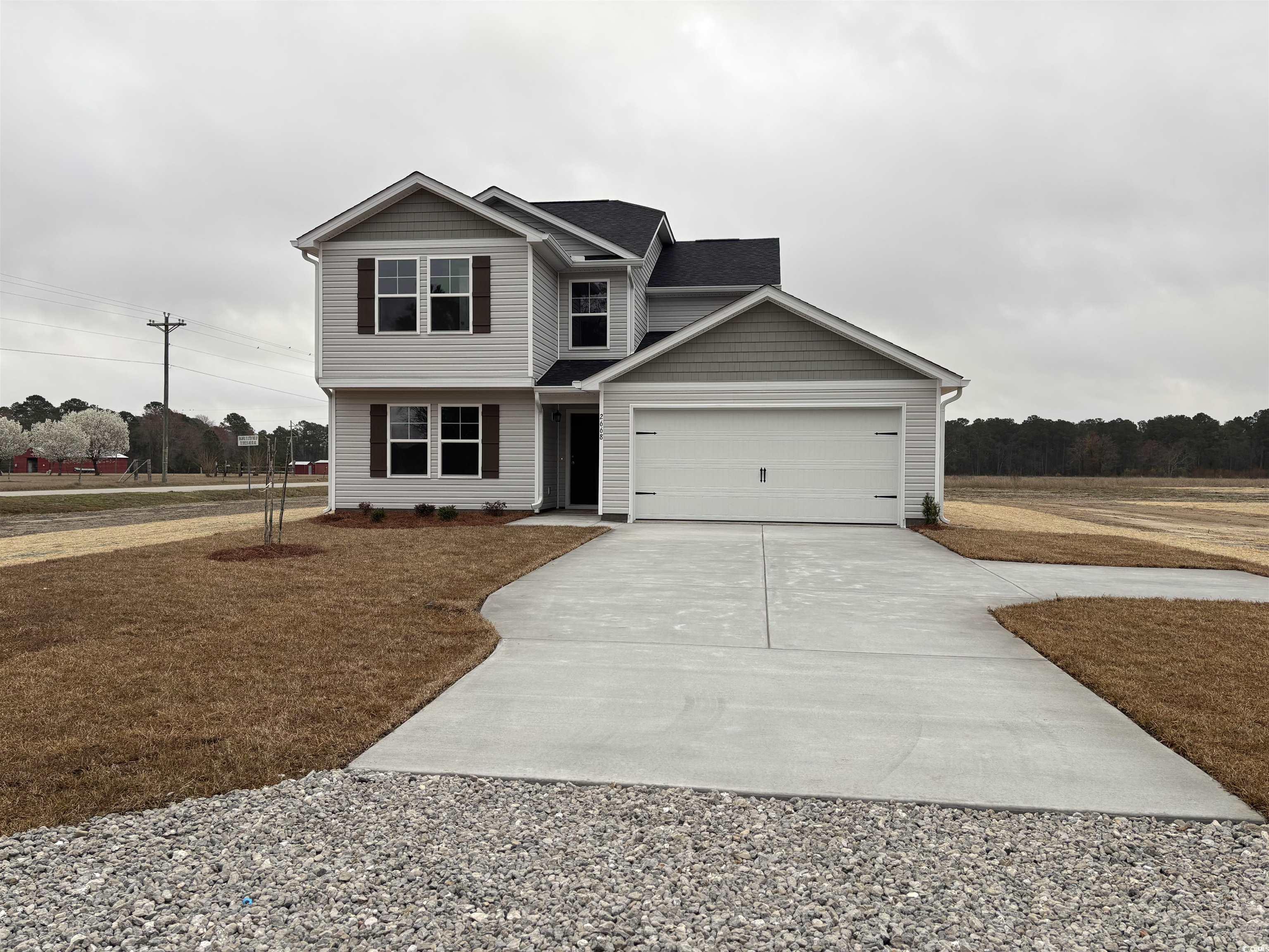 View of front facade featuring driveway, a garage, and view of wooded area