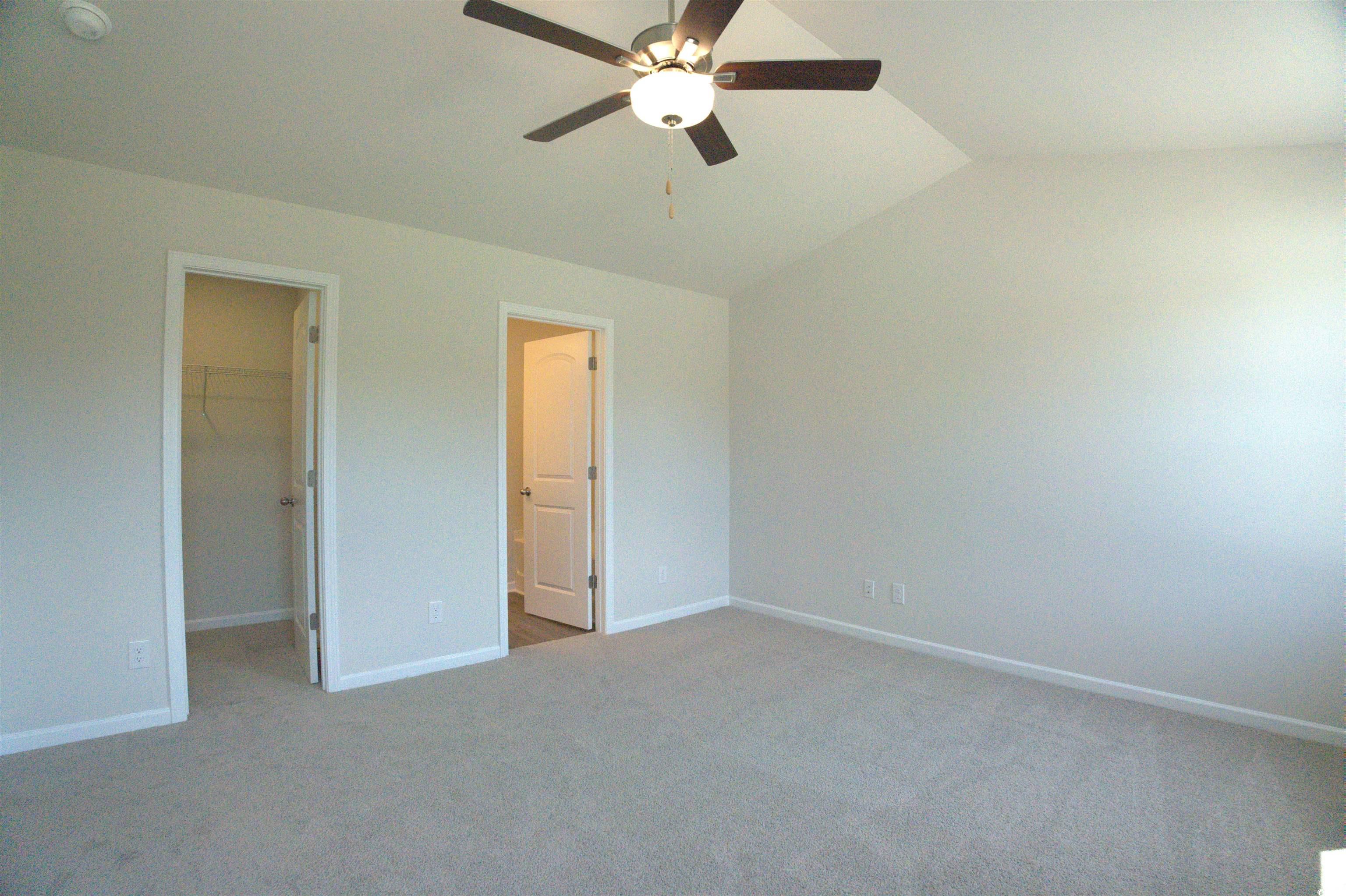 2668 Tansy Road Loris, SC 29569 - Photo 10 of 11 Unfurnished bedroom with a spacious closet, lofted ceiling, light carpet, and a ceiling fan