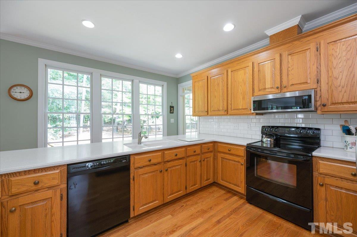 7025 Spring Ridge Road Cary, NC 27518 - Photo 14 of 35 a kitchen with stainless steel appliances granite countertop wooden cabinets a stove a sink and a window