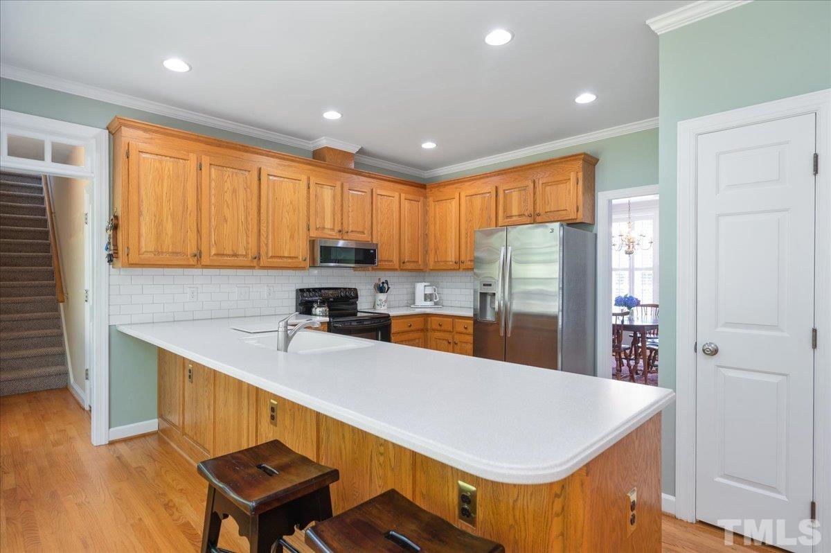 7025 Spring Ridge Road Cary, NC 27518 - Photo 16 of 35 a kitchen with stainless steel appliances granite countertop a refrigerator a sink dishwasher a stove with wooden cabinets and floor