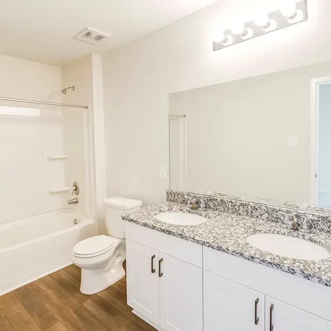 a bathroom with a granite countertop sink toilet a mirror and bathtub