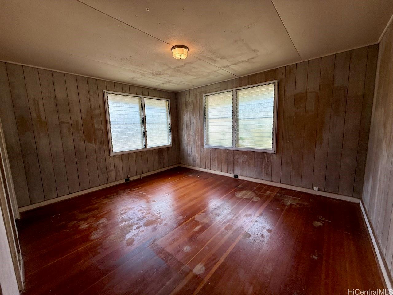 5265 Manauwea Street Honolulu, HI 96821 - Photo 12 of 24 an empty room with wooden floor and windows with curtains
