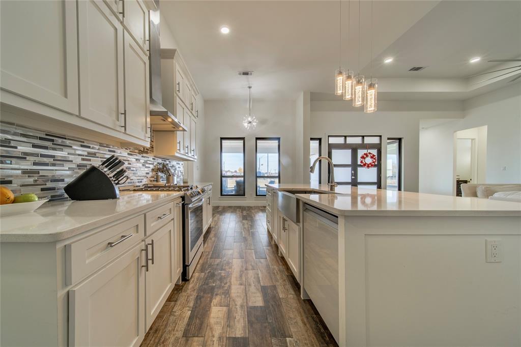 165 Ranch House Road Rockwall, TX 75032 - Photo 10 of 40 a kitchen with counter top space a sink wooden floor and stainless steel appliances