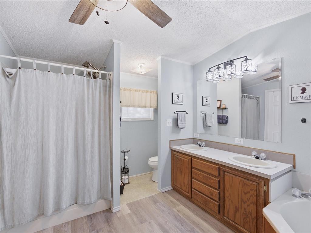 3275 Finis Road Graham, TX 76450 - Photo 17 of 36 a spacious bathroom with a double vanity sink a mirror a toilet and a shower