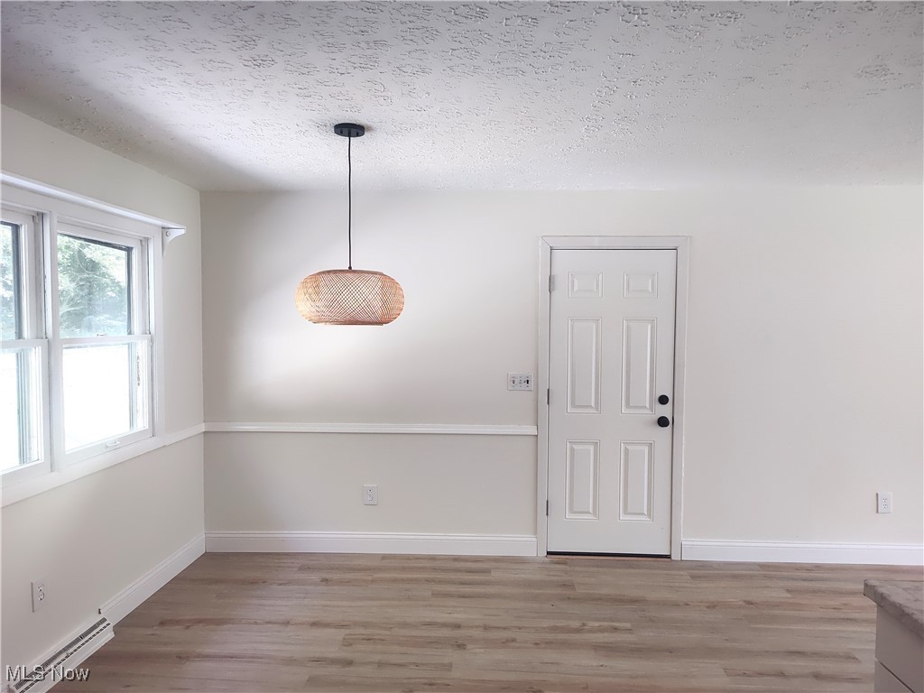 8016 Ninevah Road Geneva, OH 44041 - Photo 28 of 45 Unfurnished dining area featuring a baseboard heating unit, a textured ceiling, and light wood-style floors