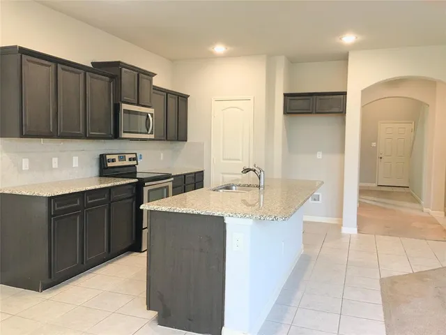 a kitchen with kitchen island granite countertop a sink and refrigerator