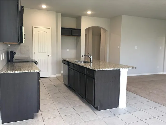 a kitchen with granite countertop a sink and a refrigerator