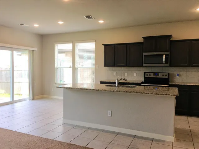 a kitchen with stainless steel appliances wooden cabinets a stove a microwave and a window