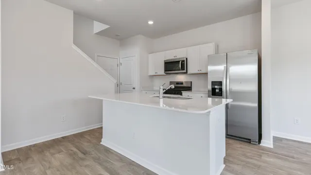a kitchen with kitchen island a sink stainless steel appliances and refrigerator