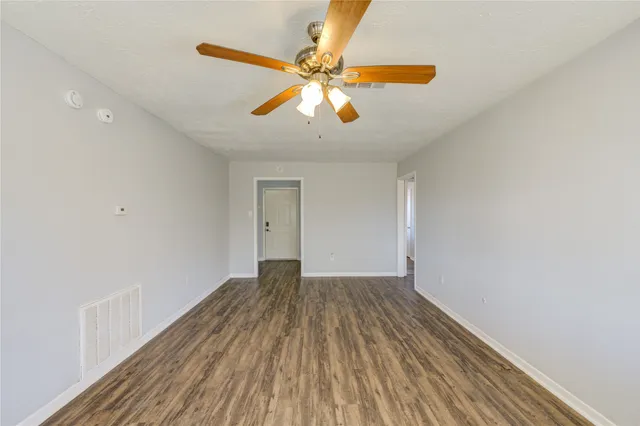 a view of an empty room with window and wooden floor