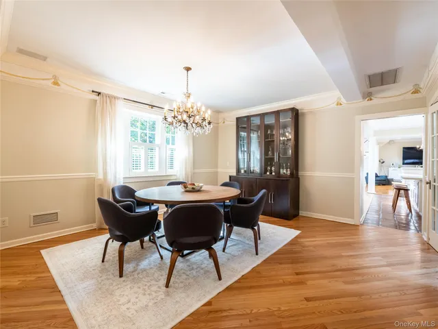 a dining room with furniture a chandelier and wooden floor