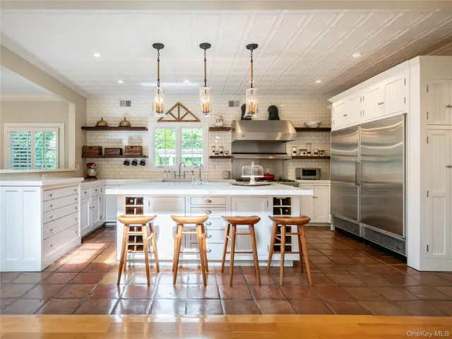 a kitchen with stainless steel appliances granite countertop a stove a refrigerator a oven a sink with island chairs and wooden floor