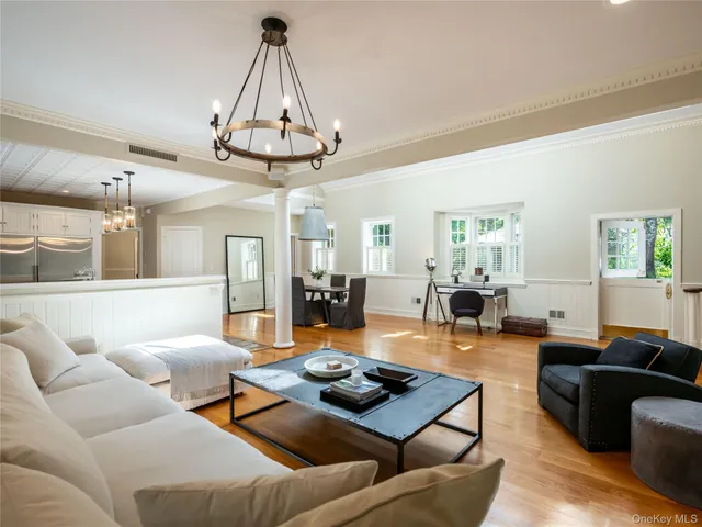 a living room with furniture kitchen view and a chandelier