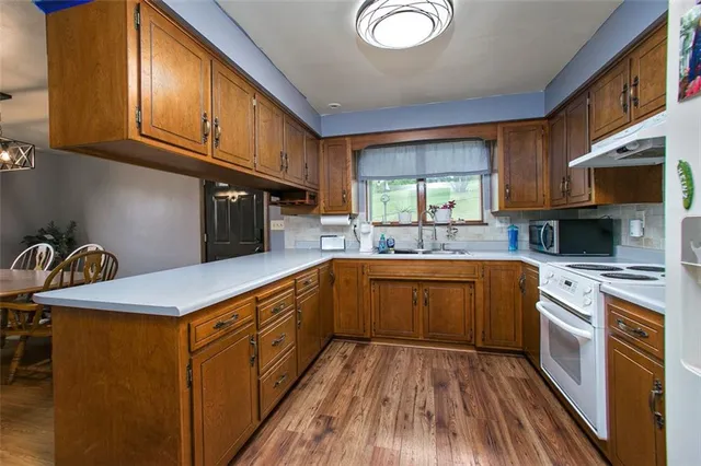 a kitchen with stainless steel appliances granite countertop a sink a stove cabinets and wooden floor