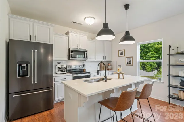 a kitchen with kitchen island a refrigerator a stove a sink and a chandelier