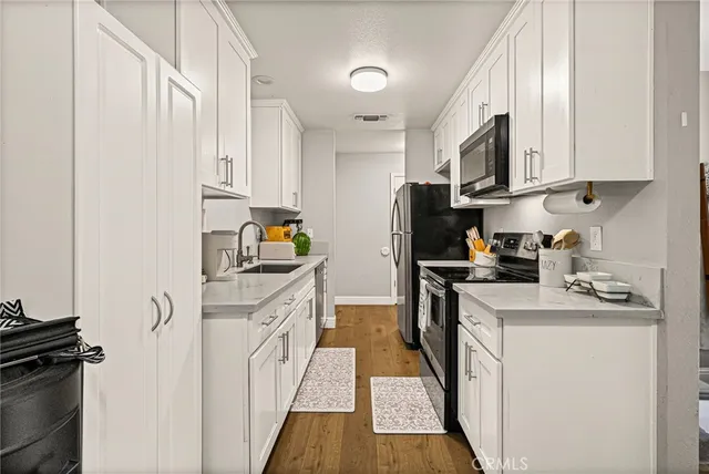 a kitchen with stainless steel appliances granite countertop a refrigerator sink and white cabinets