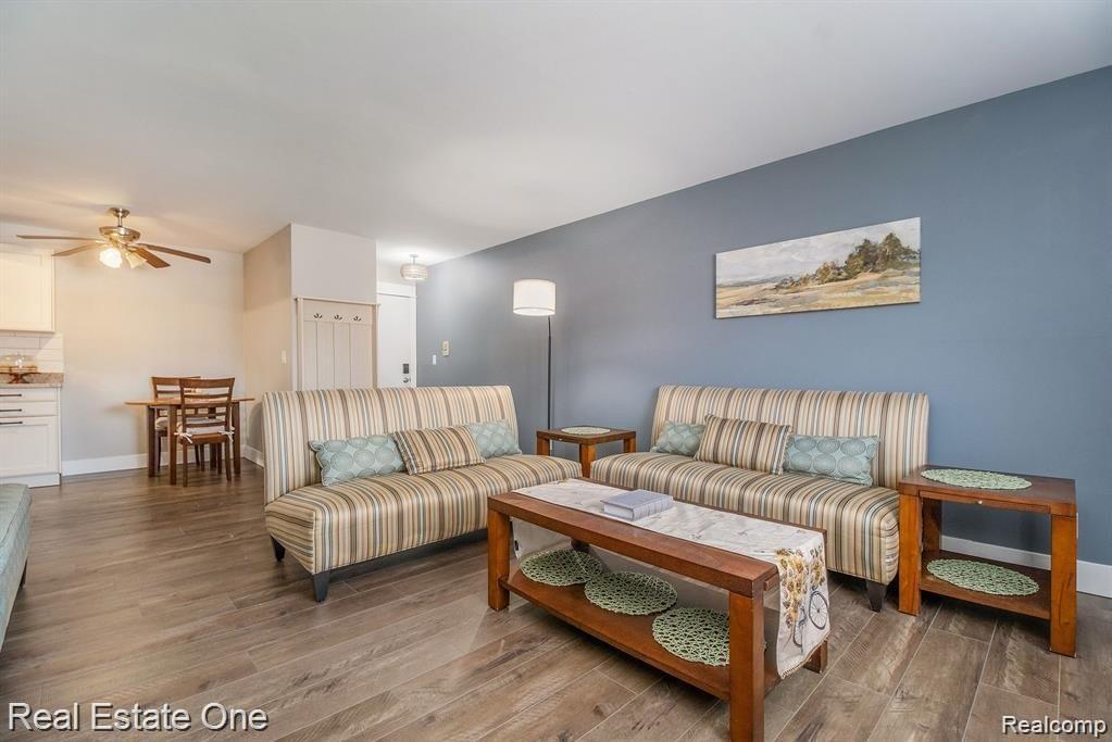 803 Plate Street, Unit 104 Rochester, MI 48307 - Photo 13 of 14 Open-concept living area with wood-finish flooring, a contemporary blue accent wall, and lighting