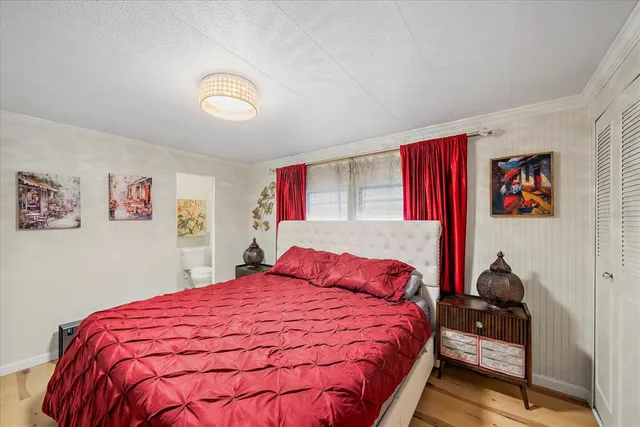 a bedroom with a bed and a flat tv screen on dresser