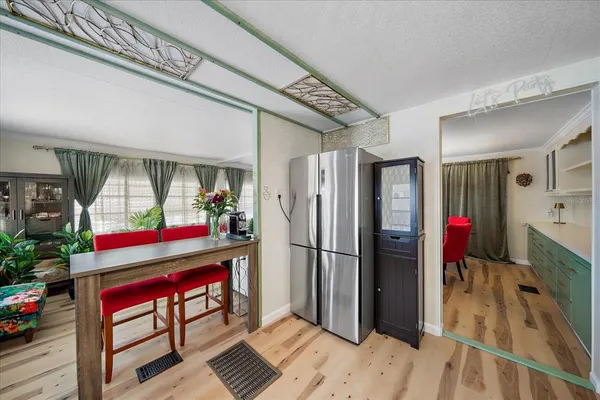 a kitchen view of a refrigerator a stove a dining table and chairs with wooden floor