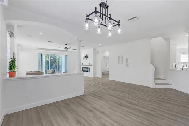 a view of an empty room and kitchen with wooden floor