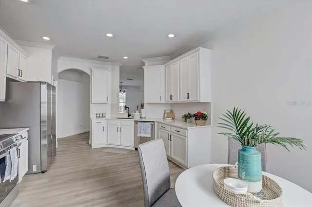 a kitchen with white cabinets and wooden floor